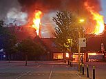 Massive blaze rips through shopping centre as roof collapses and residents are told to keep their windows shut