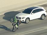 Dystopian Mad Max scene on LA freeway as car thief in stolen SUV is surrounded by huge gang of illegal dirt bikers